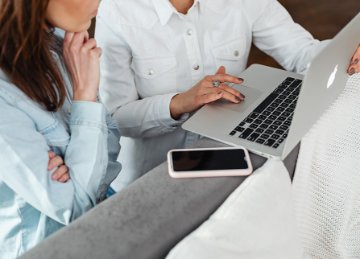 A business meeting between two people with one lady holding a laptop